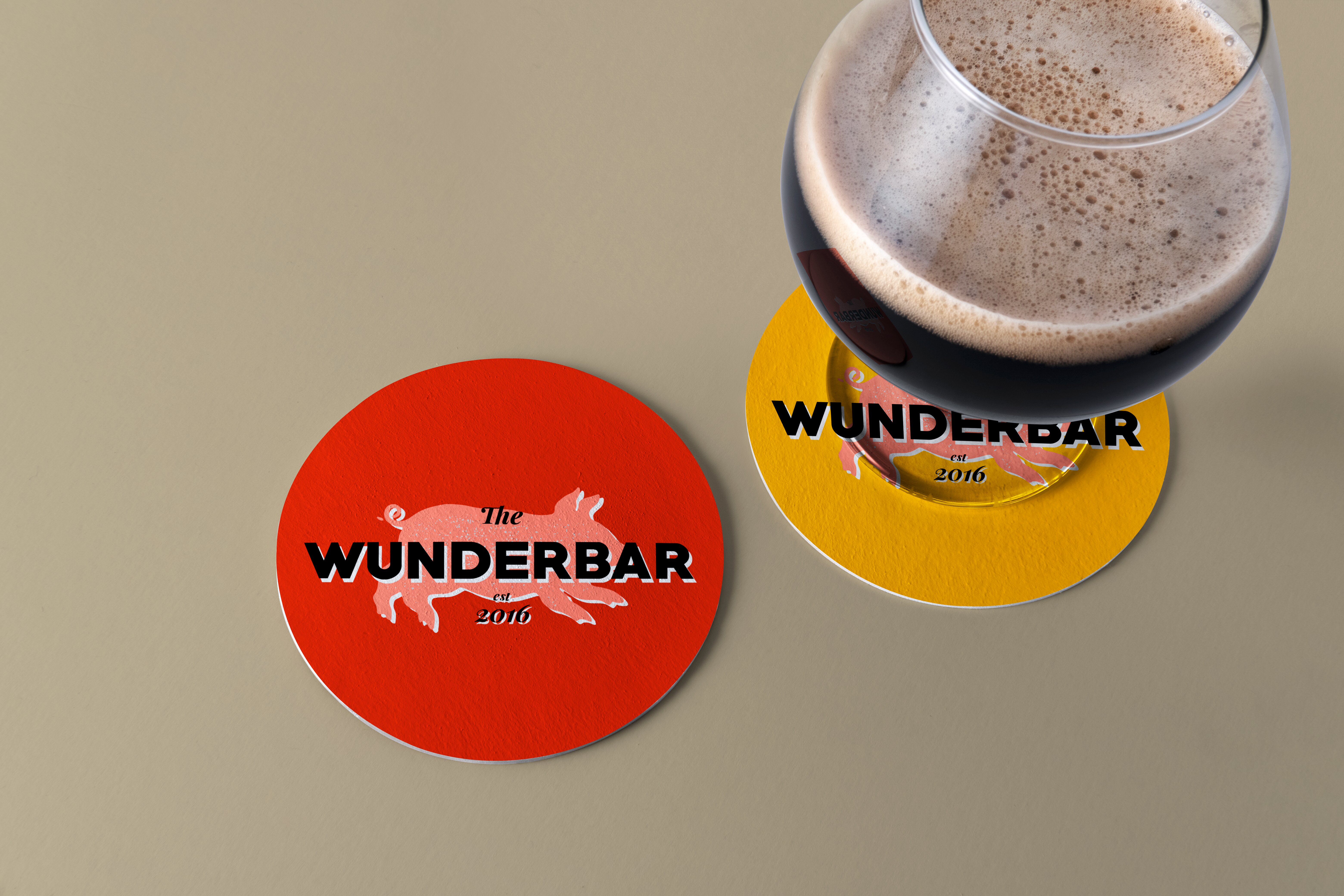 A beer glass with 2 beer coasters displaying the Wunderbar logo. One red and one yellow.